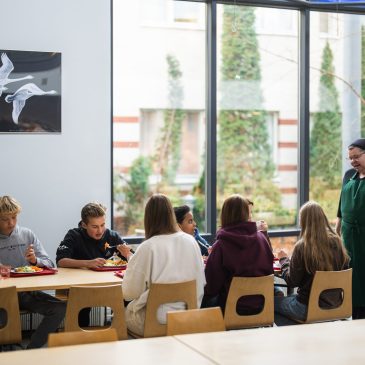 Oppilaat ja keittiöhenkilökuntaa ruokalassa